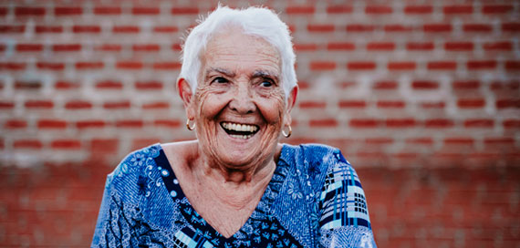Happy older woman standing in front of brick wall